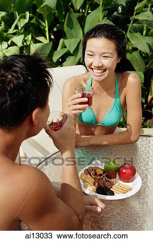 Couple sitting and drinking, snacks on table in front of them View Large Photo Image Stock Image - Couple sitting and drinking, snacks on table in front of them. Fotosearch