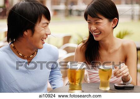 Couple sitting at cafe, drinks in hand View Large Photo Image Picture - Couple sitting at cafe, drinks in hand. Fotosearch
