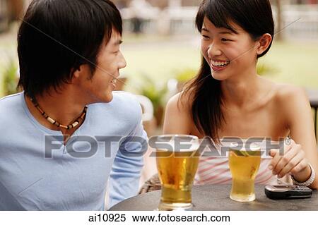 Couple sitting at cafe, looking at each other, drinks in hand View Large Photo Image Stock Photography - Couple sitting at cafe, looking at each other, drinks in hand. Fotosearch