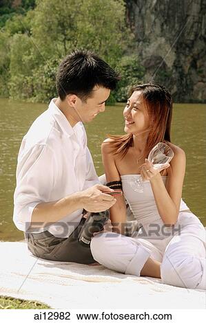 Couple sitting by a lake, with wine bottle and wine glass View Large Photo Image Stock Image - Couple sitting by a lake, with wine bottle and wine glass. Fotosearch