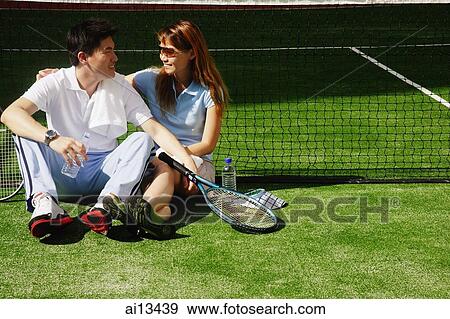 Couple sitting down on tennis court, looking at each other View Large Photo Image Stock Photo - Couple sitting down on tennis court, looking at each other. Fotosearch