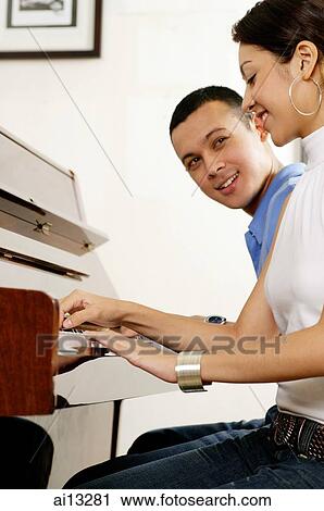 Stock Image - Couple sitting down playing the piano. Fotosearch