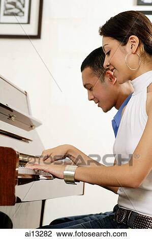 Couple sitting down playing the piano View Large Photo Image Stock Image - Couple sitting down playing the piano. Fotosearch