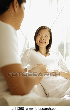 Couple sitting face to face, holding cups and saucers View Large Photo Image Stock Photo - Couple sitting face to face, holding cups and saucers. Fotosearch