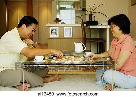 Couple sitting on floor, playing Chinese chess at home View Large Photo Image Stock Image - Couple sitting on floor, playing Chinese chess at home. Fotosearch