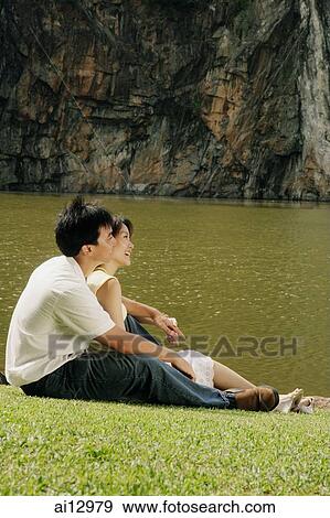 Couple sitting on grass, looking away View Large Photo Image Stock Photo - Couple sitting on grass, looking away. Fotosearch