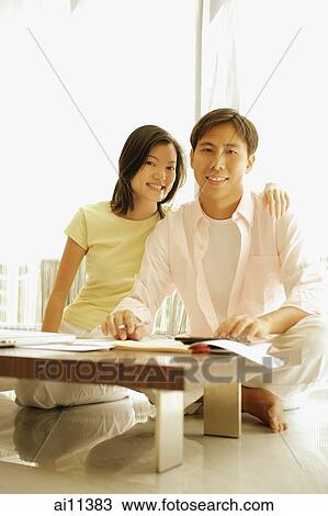 Couple sitting side by side at home, documents and papers in front of them. View Large Photo Image Stock Image - Couple sitting side by side at home, documents and papers in front of them.. Fotosearch