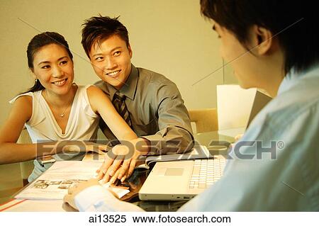Couple sitting side by side at table, facing another man View Large Photo Image Stock Photography - Couple sitting side by side at table, facing another man. Fotosearch