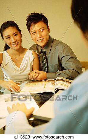 Couple sitting side by side, facing another man View Large Photo Image Stock Image - Couple sitting side by side, facing another man. Fotosearch