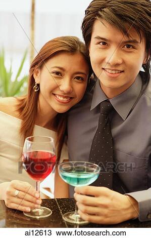 Couple sitting side by side, holding drinks and looking at camera View Large Photo Image Stock Image - Couple sitting side by side, holding drinks and looking at camera. Fotosearch