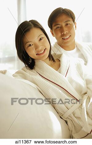 Couple sitting side by side, looking at camera View Large Photo Image Stock Photo - Couple sitting side by side, looking at camera. Fotosearch