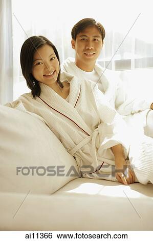 Stock Photograph - Couple sitting side by side, looking at camera. Fotosearch