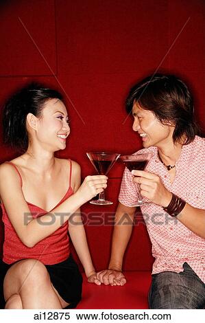 Couple sitting side by side, toasting with drinks View Large Photo Image Stock Photography - Couple sitting side by side, toasting with drinks. Fotosearch