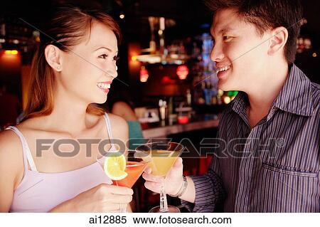 Couple standing and holding drinks View Large Photo Image Stock Photography - Couple standing and holding drinks. Fotosearch