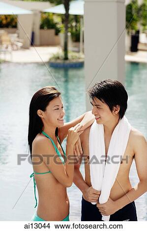 Couple standing at poolside, woman with arm on man's shoulder View Large Photo Image Picture - Couple standing at poolside, woman with arm on man's shoulder. Fotosearch