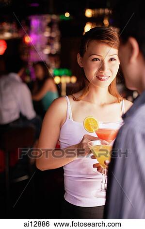 Couple standing, holding drinks, over the shoulder view View Large Photo Image Stock Photograph - Couple standing, holding drinks, over the shoulder view. Fotosearch