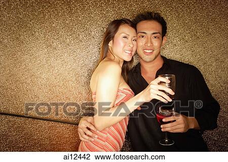 Couple standing with wine glass, looking at camera View Large Photo Image Stock Image - Couple standing with wine glass, looking at camera. Fotosearch