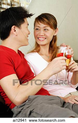Stock Image -  Couple toasting with champagne, looking at each other. Fotosearch