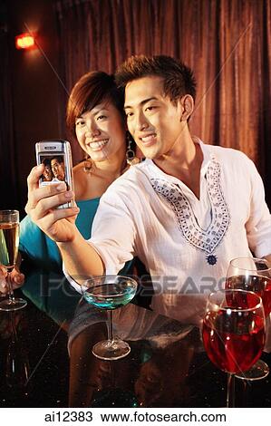 Couple using camera phone, posing for picture View Large Photo Image Stock Image - Couple using camera phone, posing for picture. Fotosearch