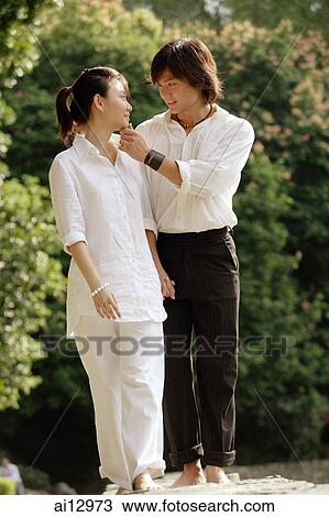 Couple walking hand in hand, man touching woman's face View Large Photo Image Stock Image - Couple walking hand in hand, man touching woman's face. Fotosearch