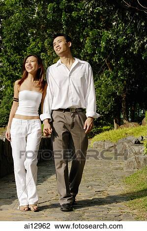 Couple walking through park, holding hands, looking away View Large Photo Image Stock Image - Couple walking through park, holding hands, looking away. Fotosearch