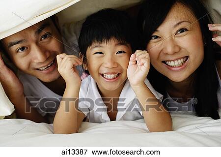Couple with young daughter, hiding under bed sheets, looking at camera View Large Photo Image Stock Photo - Couple with young daughter, hiding under bed sheets, looking at camera. Fotosearch