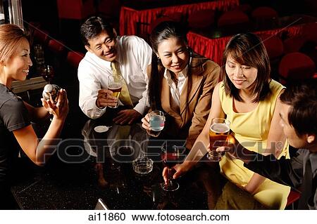 Couples drinking at bar, bartender shaking cocktail mixer View Large Photo Image Stock Image - Couples drinking at bar, bartender shaking cocktail mixer. Fotosearch