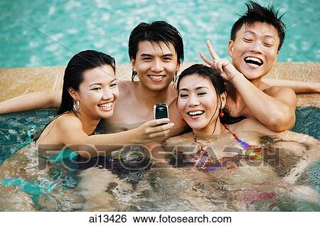 Couples in swimming pool, looking at mobile phone View Large Photo Image Stock Photograph - Couples in swimming pool, looking at mobile phone. Fotosearch