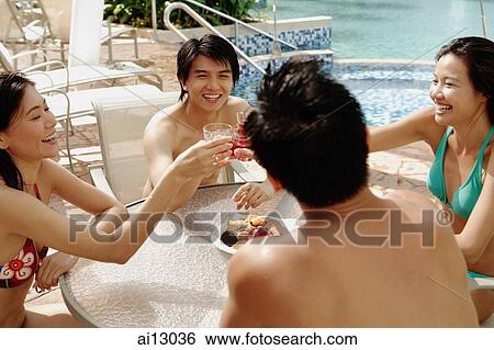 Couples sitting and toasting drinks at poolside table View Large Photo Image Stock Photograph - Couples sitting and toasting drinks at poolside table. Fotosearch