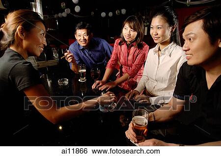 Stock Photograph - Couples sitting at bar, bartender serving them. Fotosearch