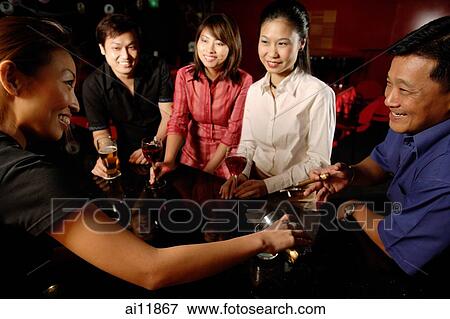 Couples sitting at bar counter, bartender serving them View Large Photo Image Stock Photo - Couples sitting at bar counter, bartender serving them. Fotosearch