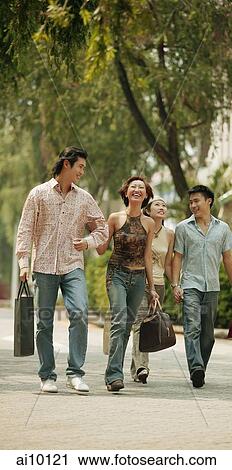 Couples walking hand in hand, carrying shopping bags View Large Photo Image Stock Image - Couples walking hand in hand, carrying shopping bags. Fotosearch