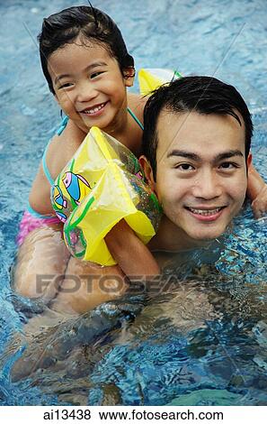 Daughter riding piggyback on father in swimming pool View Large Photo Image Stock Photo - Daughter riding piggyback on father in swimming pool. Fotosearch