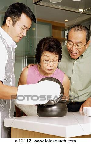 Elderly couple looking at food prepared by young man View Large Photo Image Stock Image - Elderly couple looking at food prepared by young man. Fotosearch