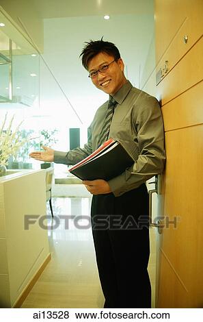 Stock Photo - Executive carrying documents, looking at camera, arm outstretched. Fotosearch