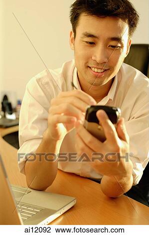 Executive sitting behind desk using PDA View Large Photo Image Stock Image - Executive sitting behind desk using PDA. Fotosearch
