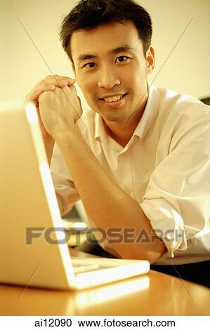 Executive sitting with elbows on desk, hands clasped, looking at camera View Large Photo Image Stock Image - Executive sitting with elbows on desk, hands clasped, looking at camera. Fotosearch