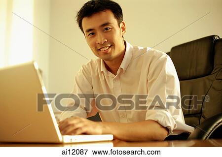 Executive using laptop, looking at camera View Large Photo Image Stock Photo - Executive using laptop, looking at camera. Fotosearch