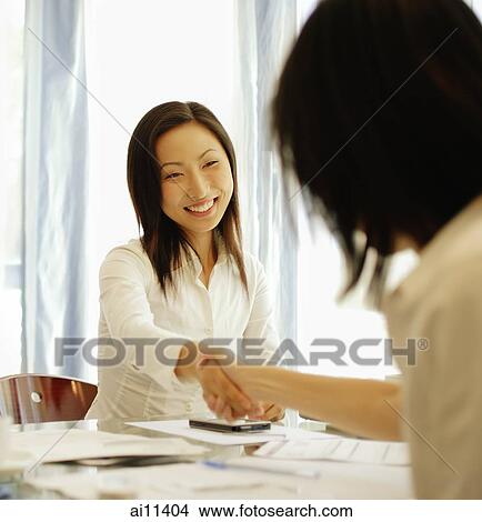 Executives shaking hands across the table. View Large Photo Image Picture - Executives shaking hands across the table.. Fotosearch