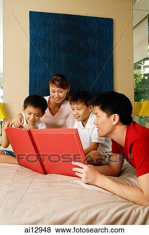 Family at home, looking at picture album View Large Photo Image Stock Photo - Family at home, looking at picture album. Fotosearch