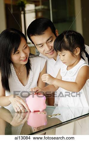 Family with one child, child putting coins into piggy bank View Large Photo Image Picture - Family with one child, child putting coins into piggy bank. Fotosearch