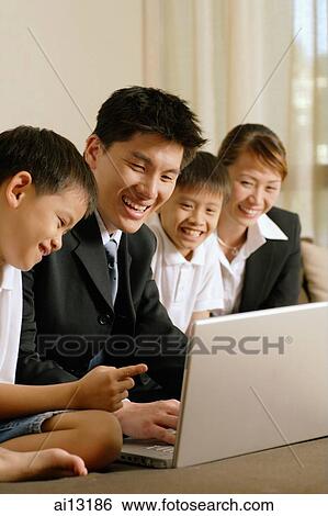 Stock Photograph - Family with two children using laptop. Fotosearch