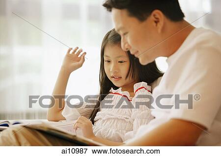 Father and daughter, sitting side by side, looking at book View Large Photo Image Stock Photo - Father and daughter, sitting side by side, looking at book. Fotosearch