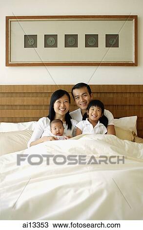 Stock Image - Father and mother with two children in bed, portrait. Fotosearch