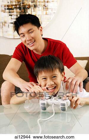 Father and son at home, boy holding game controller View Large Photo Image Picture - Father and son at home, boy holding game controller. Fotosearch