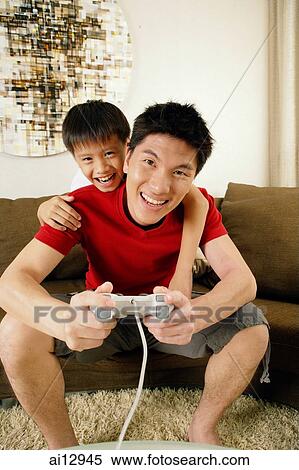 Father and son at home, father holding game controller View Large Photo Image Stock Photography - Father and son at home, father holding game controller. Fotosearch