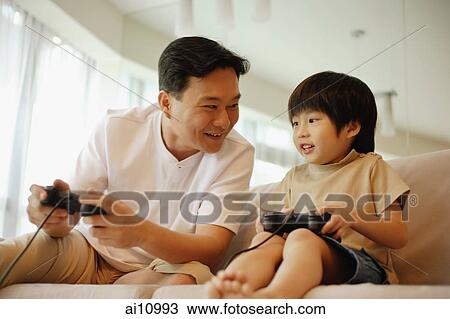 Father and son sitting on sofa, playing with video game View Large Photo Image Stock Image - Father and son sitting on sofa, playing with video game. Fotosearch