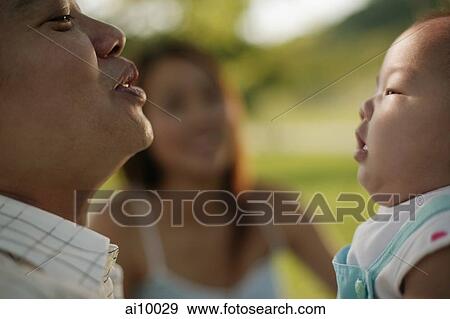 Father bonding with baby, mother in the background. View Large Photo Image Stock Photo - Father bonding with baby, mother in the background.. Fotosearch
