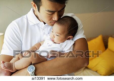 Stock Image - Father carrying baby daughter, portrait. Fotosearch