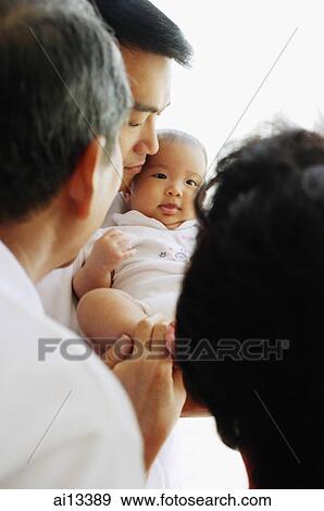 Stock Photo - Father carrying baby daughter, grandparents in the foreground. Fotosearch